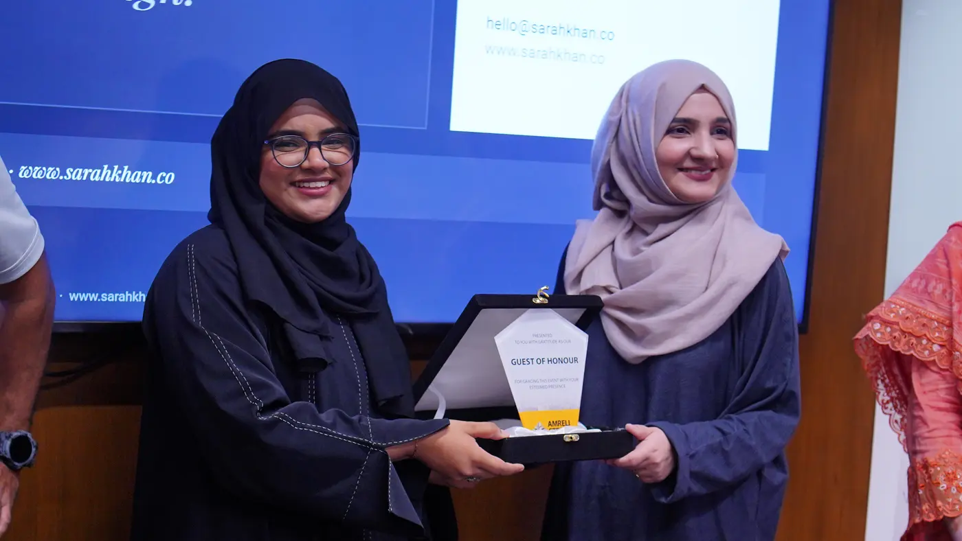 An Amreli Steels representative presenting a Guest of Honour plaque to the facilitator in front of the session screen.