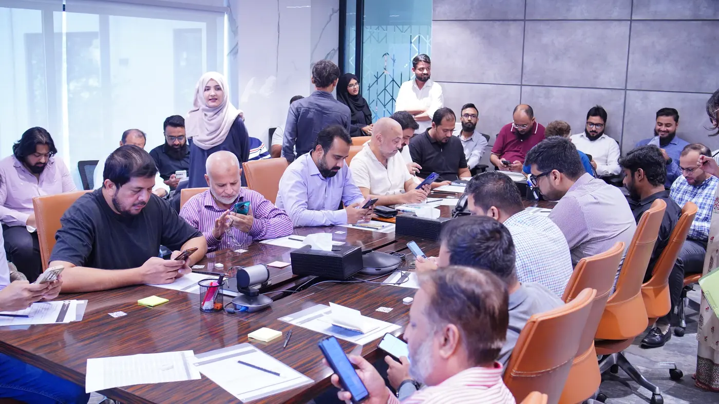 Amreli Steels leaders around the boardroom table taking the assessment on their phones.