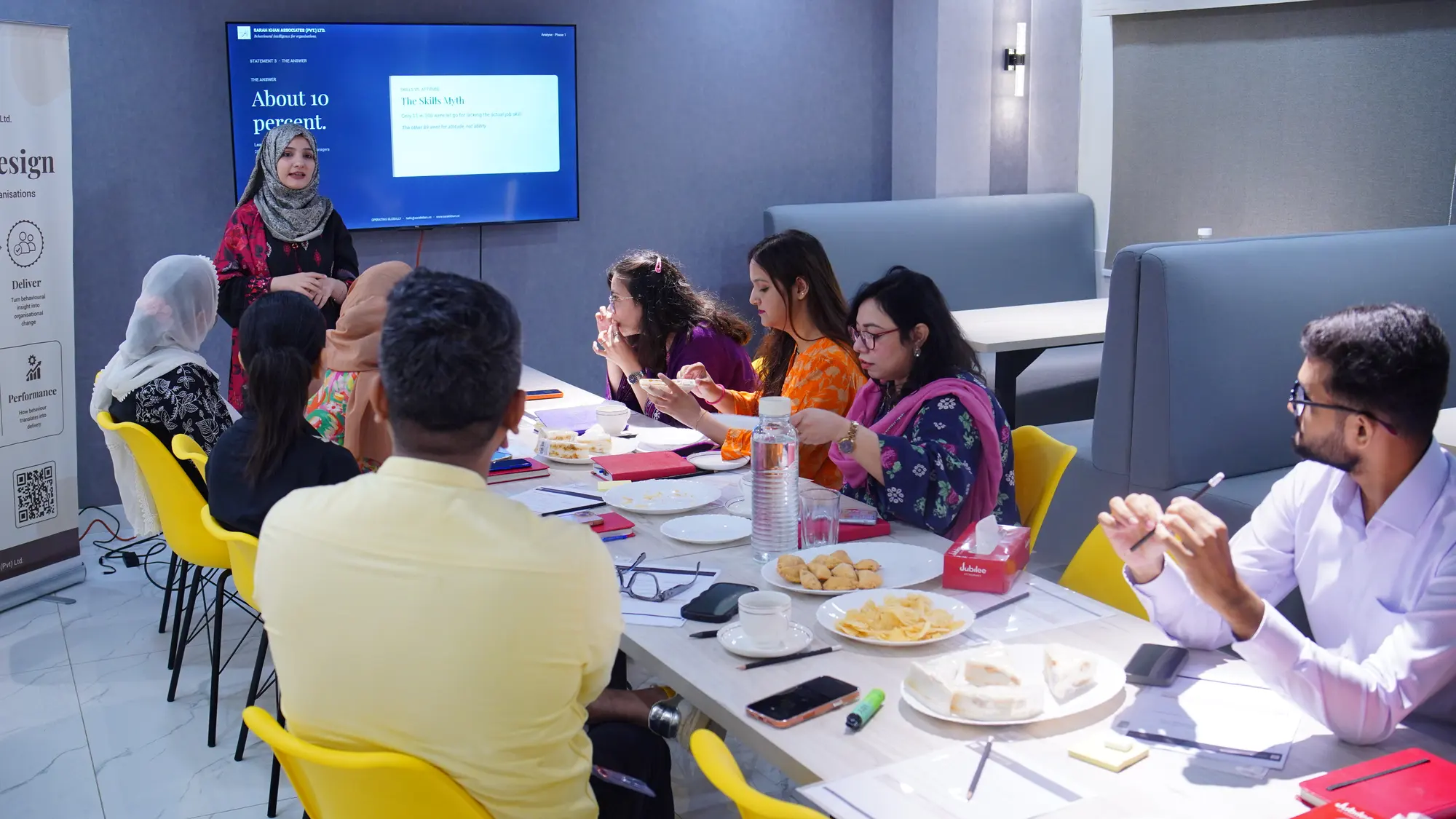 A facilitator standing by the screen while the Jubilee Life HR team sits around the table.