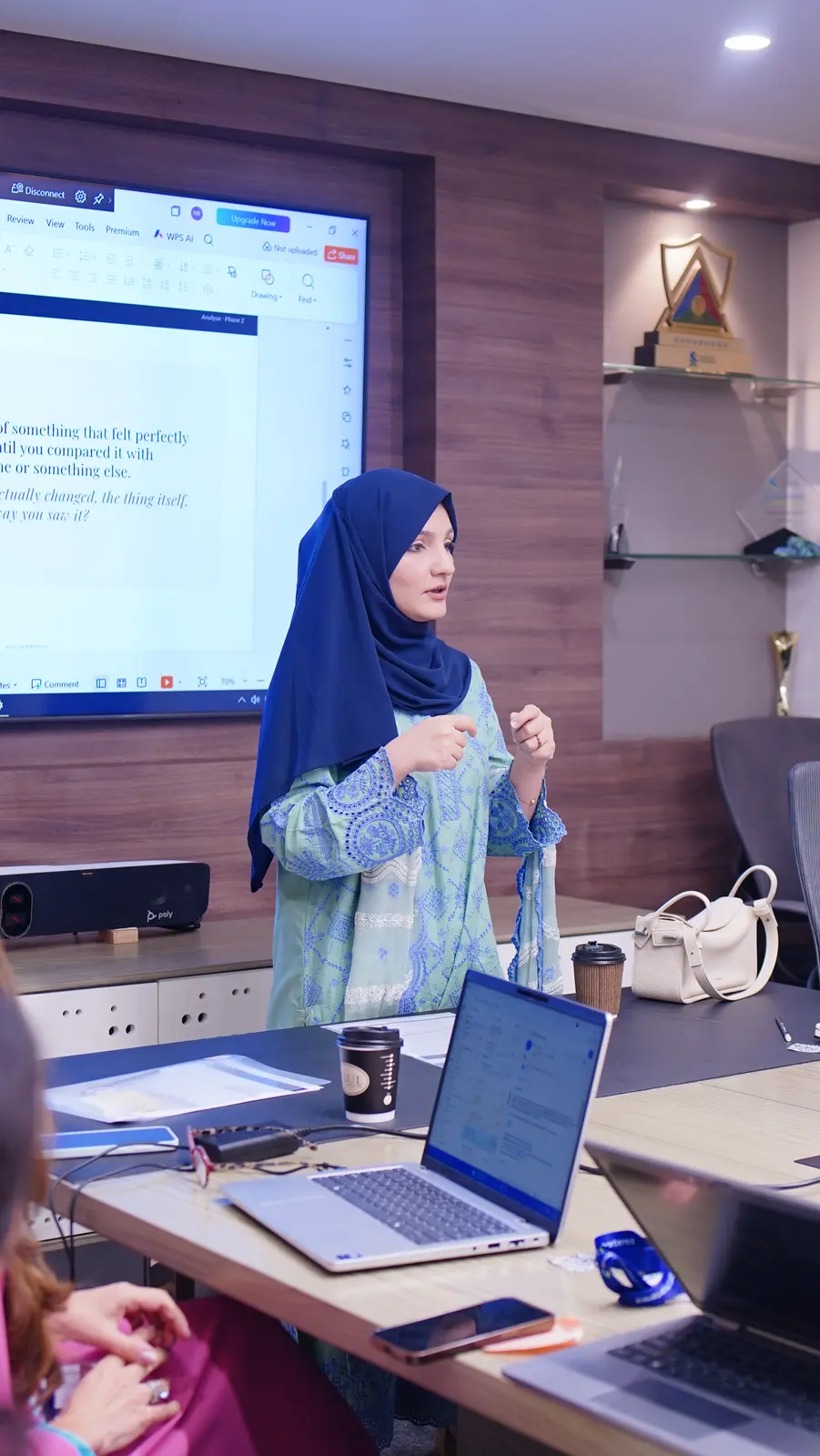 A facilitator speaking to the Standard Chartered leadership session, with a reflection prompt on the screen behind her.