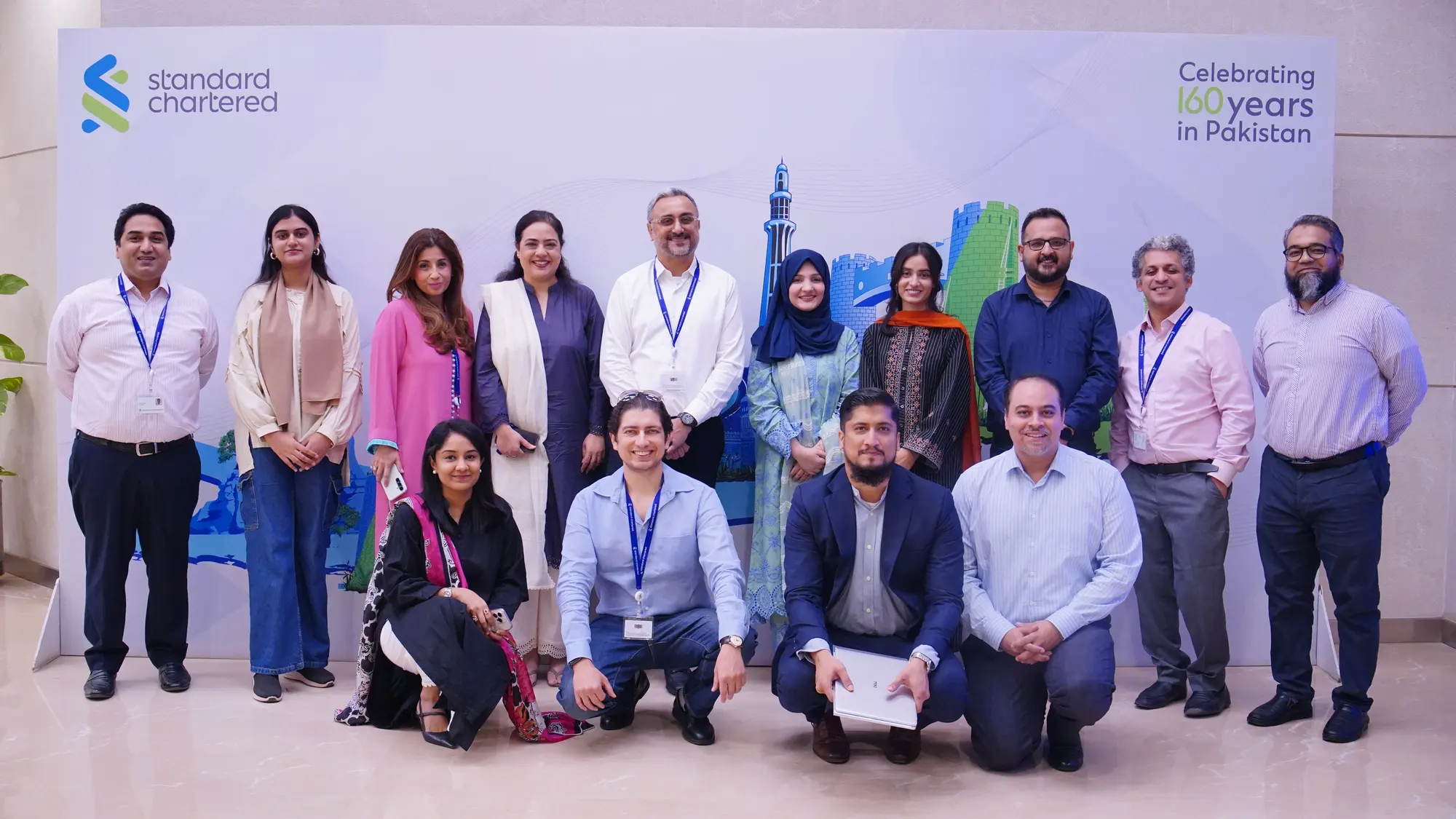 The Standard Chartered leadership group posed in front of a banner marking one hundred years in Pakistan.